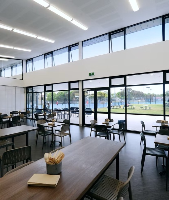Cafe and function area with timber tables and tennis court views